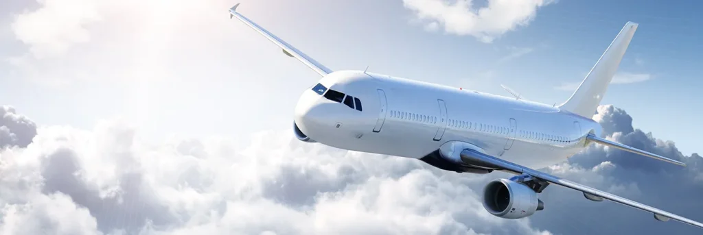 Un avion de ligne blanc en vol dans un ciel partiellement nuageux. L'avion semble naviguer en douceur au-dessus des nuages, évoquant un voyage d'affaires confortable et professionnel.