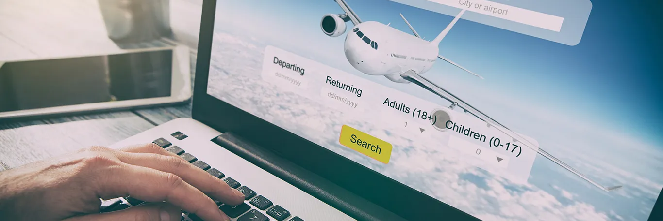 Personne utilisant un ordinateur portable pour rechercher des vols en ligne, avec une image d'un avion en vol en arrière-plan sur l'écran. L'image illustre la facilité et l'efficacité des services de réservation de voyages d'affaires en ligne offerts par CTA Business Travel.