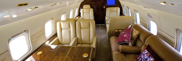 Intérieur luxueux d'un jet privé avec des sièges en cuir et une table en bois. L'image illustre le confort et l'exclusivité des services de voyage VIP offerts par CTA Business Travel pour les déplacements professionnels haut de gamme.