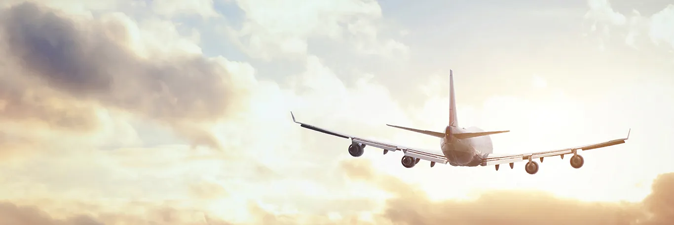 Avion en vol avec le soleil couchant à l'arrière-plan et des nuages dans le ciel. L'image évoque les voyages d'affaires internationaux, mettant en avant l'engagement de CTA Business Travel à offrir des services de gestion de déplacements professionnels efficaces et agréables.