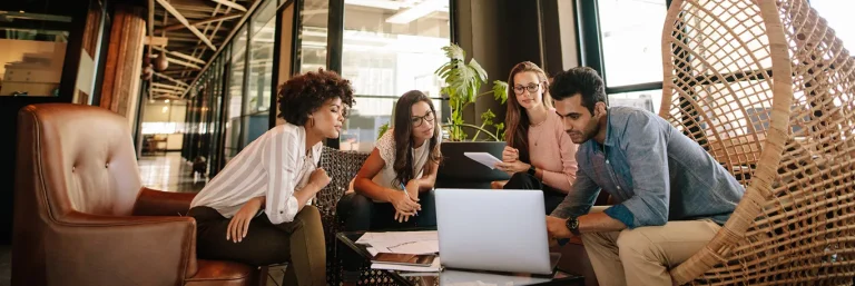 Équipe de professionnels collaborant autour d'un ordinateur portable dans un espace de travail moderne et confortable. L'image représente la planification et la coordination des voyages d'affaires, illustrant les services de CTA Business Travel pour organiser efficacement les déplacements professionnels.