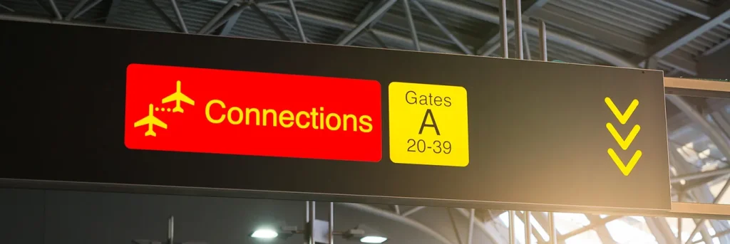 Panneau de signalisation dans un aéroport indiquant les connexions et les portes d'embarquement de la zone A. L'image représente la logistique des voyages d'affaires et l'importance des correspondances bien organisées, illustrant les services de CTA Business Travel pour assurer des déplacements professionnels fluides et efficaces.