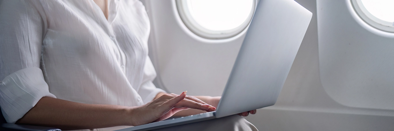 Personne travaillant sur un ordinateur portable à bord d'un avion. L'image met en avant la productivité en déplacement, soulignant la capacité de CTA Business Travel à soutenir les professionnels dans leurs voyages d'affaires en offrant des services qui permettent de rester connecté et efficace en vol.