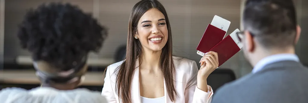 Femme souriante tenant des passeports et des billets d'avion, face à deux personnes dans un environnement professionnel. L'image symbolise la gestion efficace des voyages d'affaires et l'assistance de CTA Business Travel pour faciliter les déplacements professionnels.