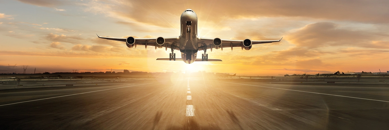 Un avion de ligne décolle sur une piste d'aéroport au lever du soleil, symbolisant les voyages d'affaires et la mobilité internationale. Le ciel est teinté de nuances de jaune et d'orange, créant une atmosphère dynamique et inspirante.