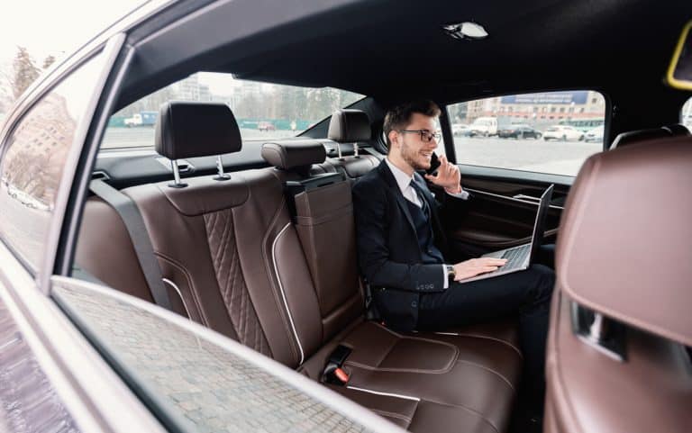Jeune homme d’affaires parlant sur le téléphone intelligent dans l’auto de luxe